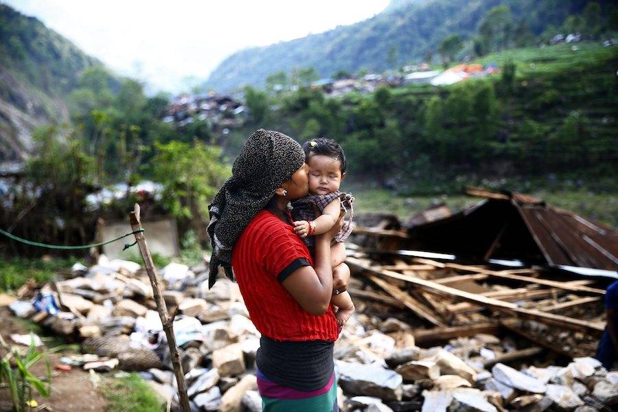 Uma nepalesa beija a filha bebé em frente aos escombros da sua casa, em Baluwa, Nepal, depois do terramoto