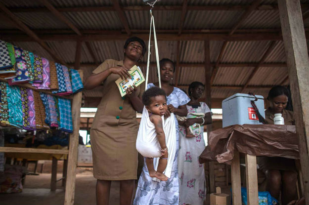 Trabalhor de saúde comunitária pesa bebês após vaciná-los. Em 2012, o Gana se tornou o primeiro país na África a introduzir simultaneamente vacinas contra doenças pneumocócicas e rotavírus. 
