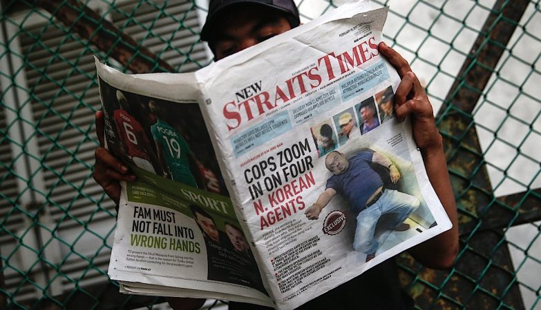 Homem na Malásia lendo o jornal Strait Times de 18 de fevereiro. Na capa, Kim Jong Nam após ser envenenado