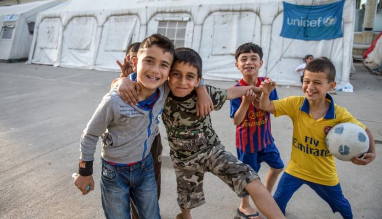 Crianças param jogo de futebol para posarem para a foto em campo de refugiados