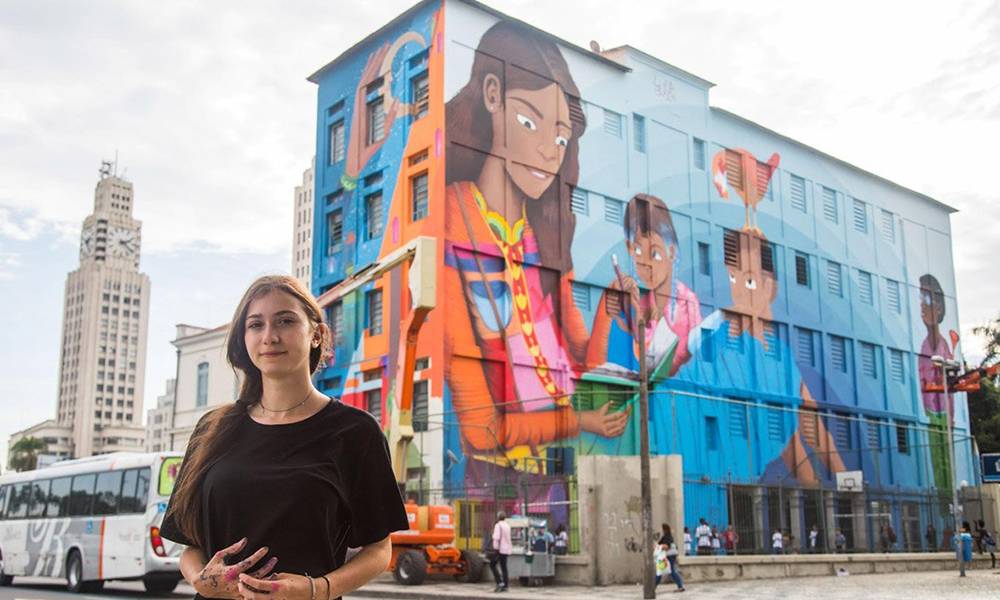 Luna Buschinelli ao lado de sua obra no Rio de Janeiro